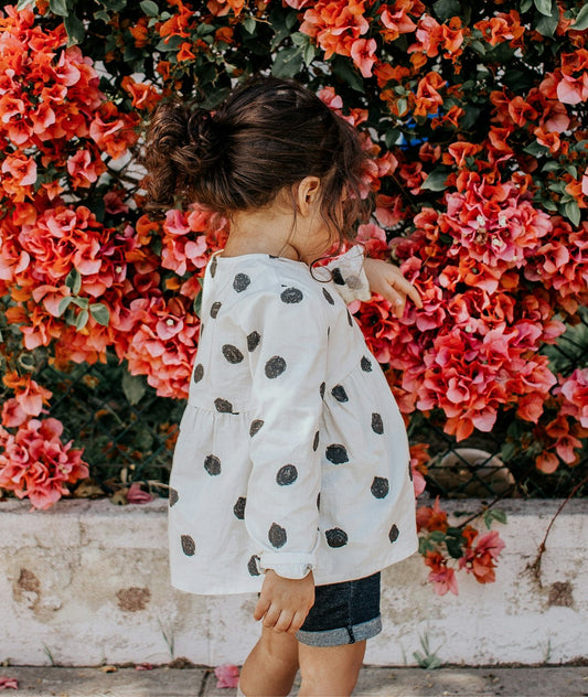 Girl in polka-dot blouse and blue shorts