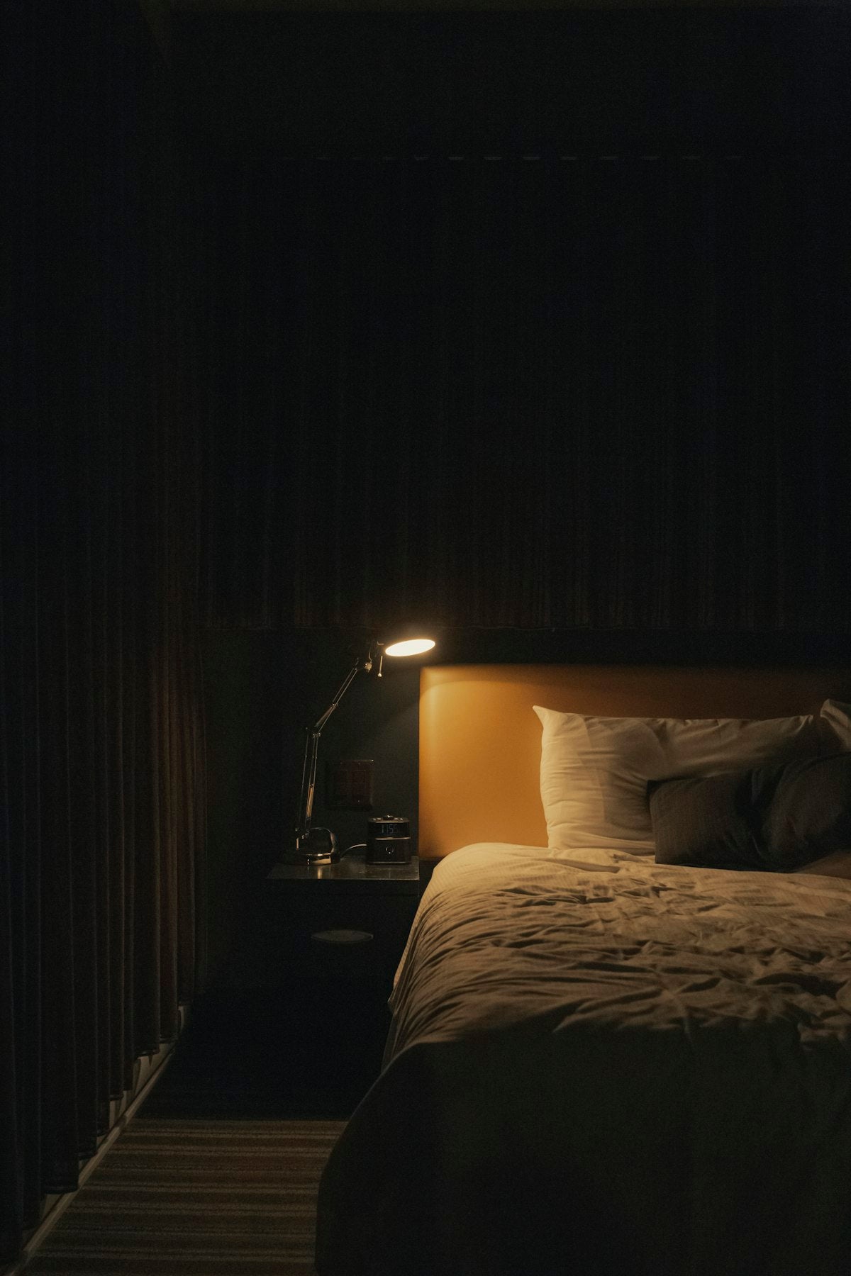Lamp glowing beside a bed at night