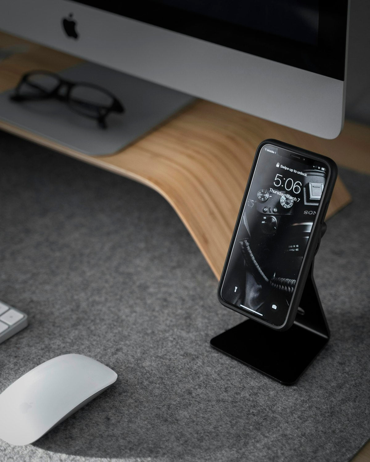 Black smartphone near white iMac desk setup