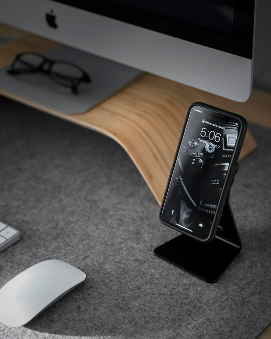 Black smartphone near white iMac desk setup
